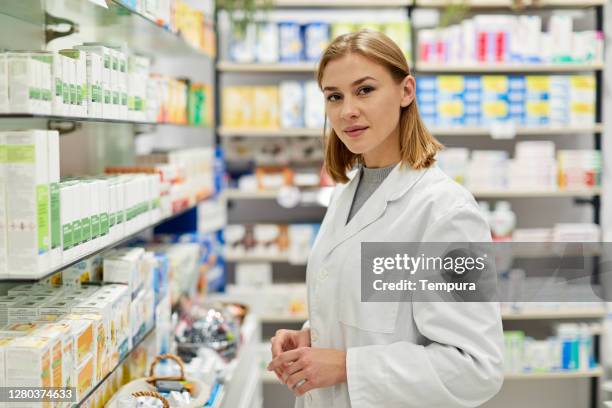 porträt eines jungen schönen apothekenangestellten, der in die kamera schaut - apothekerin stock-fotos und bilder