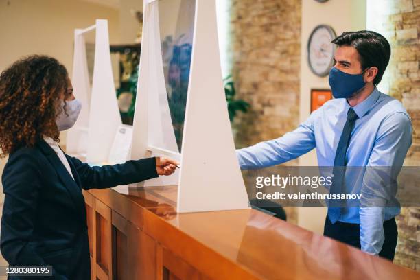 receptionist giving card key to hotel guest and explains the anti-epidemic measures in the hotel after covid-19 pandemic - bulgaria coronavirus stock pictures, royalty-free photos & images
