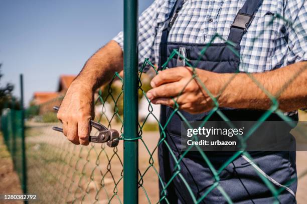 senior man building fence - metal fence stock pictures, royalty-free photos & images