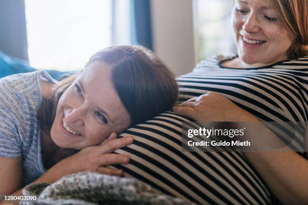 woman feeling movements of baby belly of her friend. - baby touching belly fotografías e imágenes de stock