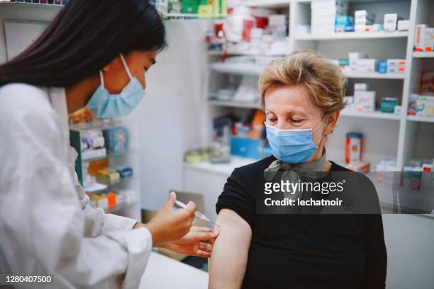enfermera asiática que da vacuna contra la gripe a un paciente de la tercera edad - vacuna contra la covid 19 fotografías e imágenes de stock