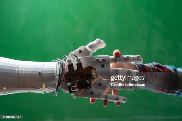 schoolboy handshaking humanoid robotic hand on green chalkboard - robot handshake stock pictures, royalty-free photos & images