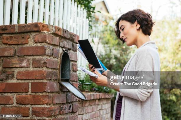 side view of beautiful young woman at mailbox - mailbox foto e immagini stock