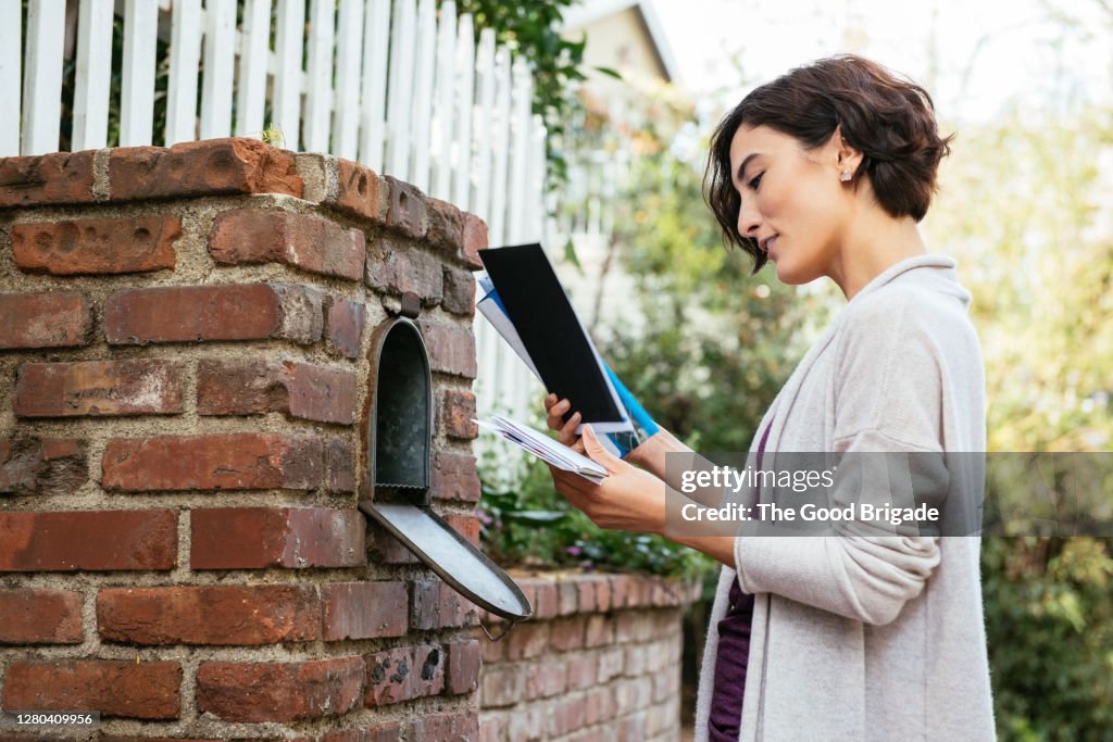 Side view of beautiful young woman at mailbox