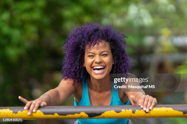 smiling young afro woman outdoors - purple hair stock pictures, royalty-free photos & images