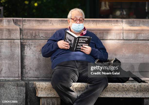 Person wears a face mask while reading Woody Allen's book "Apropos of Nothing" as the city continues the re-opening efforts following restrictions...