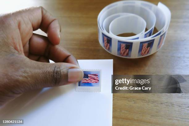 woman places postage stamp on envelope - postage stamp stock pictures, royalty-free photos & images