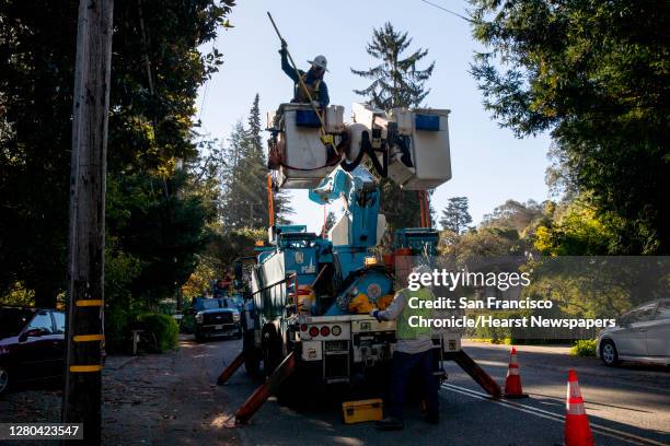 Line inspector Kirk Thompson works to clear lines so crews can begin removing a tree that crashed into live power lines along Mountain Boulevard in...
