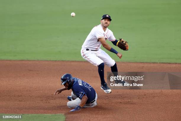 Carlos Correa of the Houston Astros turns a double play as Manuel Margot of the Tampa Bay Rays is out at second during the eighth inning in Game Five...