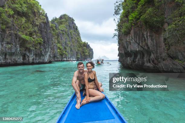 couples attrayants de jeune adulte s’asseyant sur l’avant d’un bateau tandis que sur des vacances tropicales - catamaran race photos et images de collection