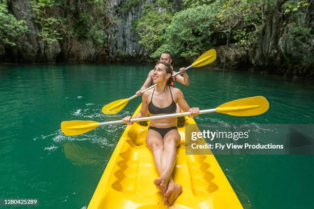 mixed race couple kayaking in the philippines - palawan stock pictures, royalty-free photos & images