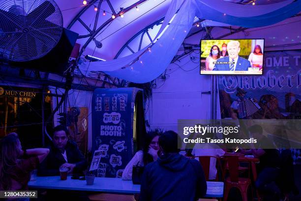 Guests at Wunder Garten Beer Garden watch as President Donald Trump speaks during a town hall on October 15, 2020 in Washington, DC. Trump and...