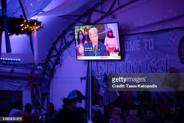 Guests at Wunder Garten Beer Garden watch as President Donald Trump speaks during a town hall on October 15, 2020 in Washington, DC. Trump and...