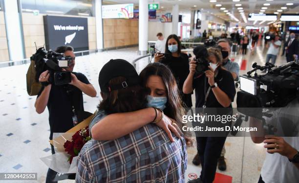 Woman wears a facemask as she hugs her loved one after arriving into the international arrivals area at Sydney's Kingsford Smith Airport from landing...