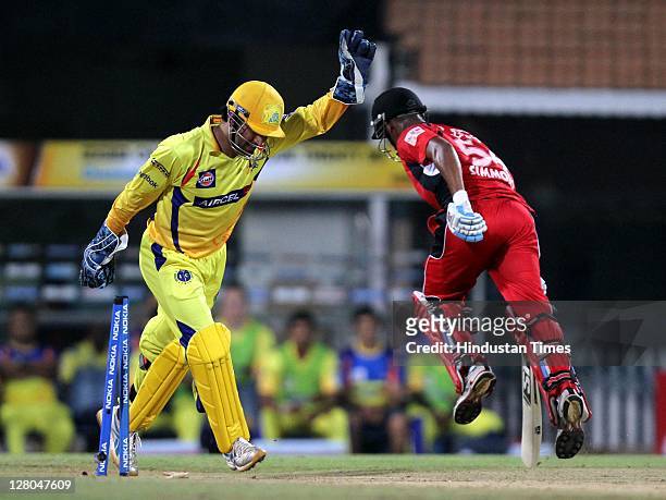 Chennai Super Kings captain MS Dhoni raises his hand in confidence as Trinidad & Tobago batsman Lendl Simmons is run out by Wriddhiman Saha during...