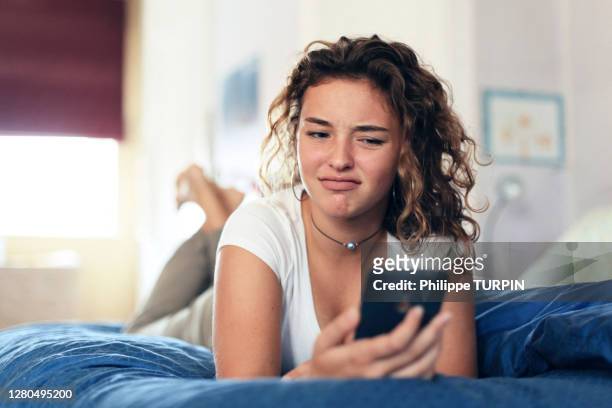 teenage girl and everyday life. in bed with smartphone - disgust ストックフォトと画像