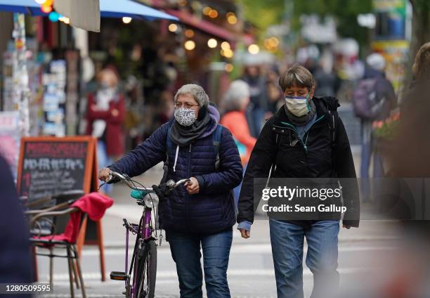 Two women, who said they did not mind being photographed, wear protective face masks while walking in Kreuzberg district during the coronavirus...