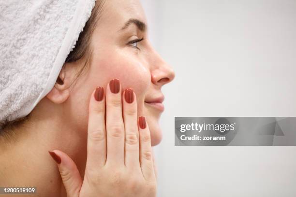 de mening van het profiel van vrouw met handdoek op nat haar dat haar gezicht raakt - facial cleanser stockfoto's en -beelden