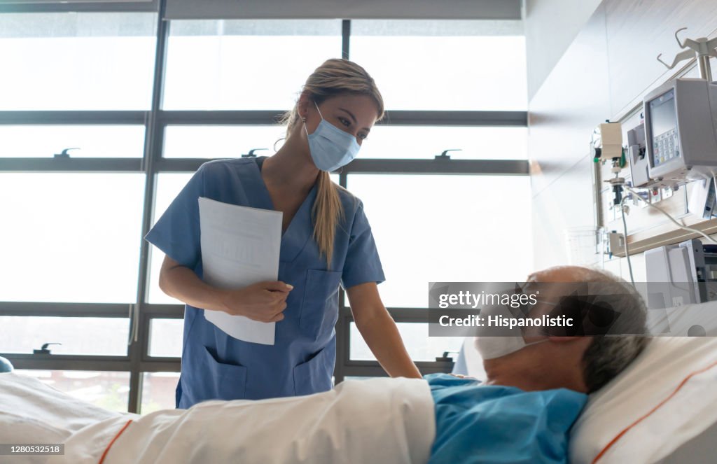 Enfermera con una mascarilla mientras revisa a un paciente en el hospital