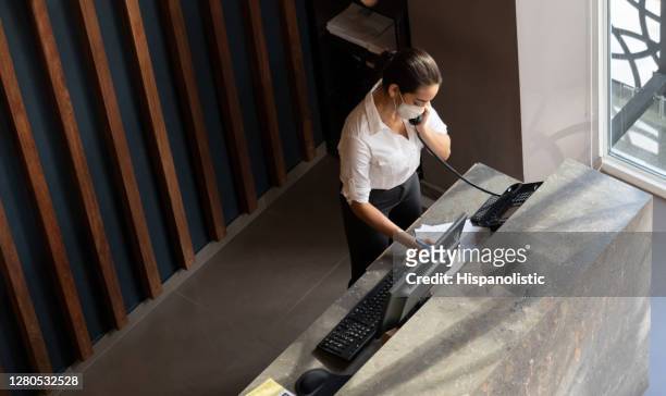 receptionist working at a hotel wearing a facemask during the covid-19 pandemic - reopening ceremony stock pictures, royalty-free photos & images
