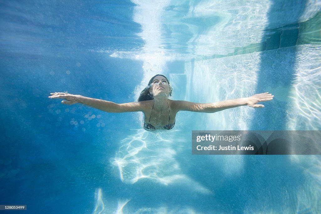 Young girl coming up from dive under pool water