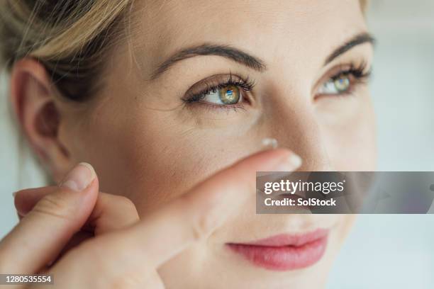 femme blond mettant dans une lentille de contact - lentilles photos et images de collection