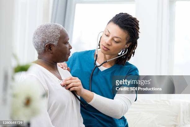 vrouwelijke thuiszorg zorgverleners controleert de vitale functies van de patiënt - listening to heartbeat stockfoto's en -beelden