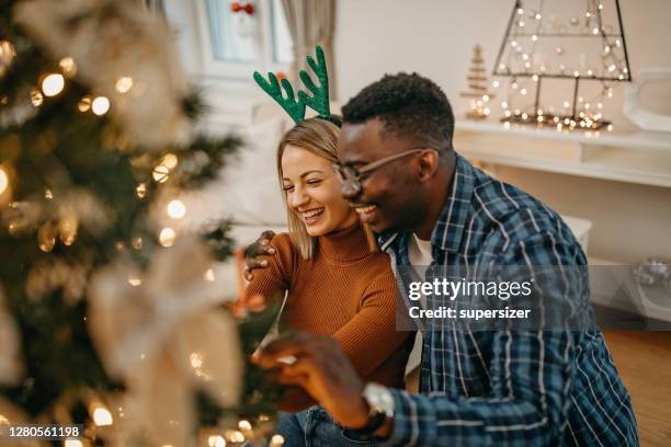 pareja decorando árbol de navidad - decorar fotografías e imágenes de stock