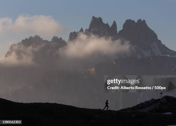 silhouette of man walking on mountain against sky - rossetto stock pictures, royalty-free photos & images