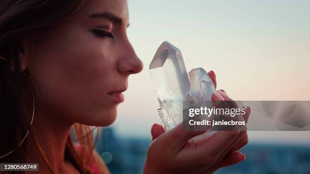 crystal healing. woman on a rooftop with city panorama. magical meditation - healing crystals stock pictures, royalty-free photos & images