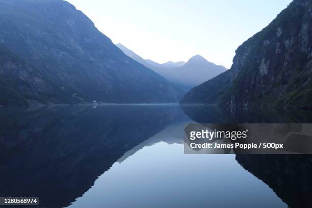 scenic view of lake and mountains against clear sky, geiranger, norway - james popple stock pictures, royalty-free photos & images
