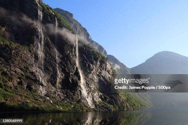 scenic view of lake and mountains against clear sky, geiranger, norway - james popple stock pictures, royalty-free photos & images
