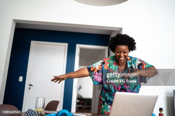 happy woamn dancing at home in front of laptop during a virtual happy hour - quarantine party stock pictures, royalty-free photos & images