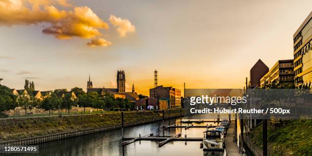 view of buildings at waterfront during sunset,duisburg,germany - duisburg stock pictures, royalty-free photos & images