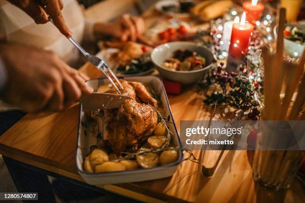 hombre sirviendo pollo asado a su esposa durante la cena de navidad - pollo asado fotografías e imágenes de stock