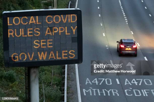 Cars drive past a sign on the M4 motorway which warns of local covid rules on October 16, 2020 in Cardiff, Wales. The Welsh First Minister Mark...