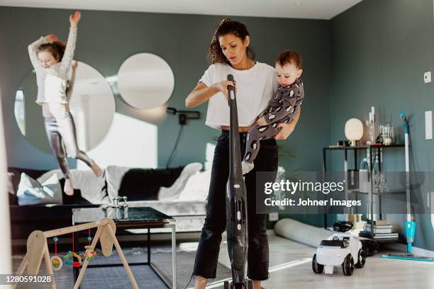 woman carrying toddler and vacuum cleaning room - sons of anarchy stock-fotos und bilder