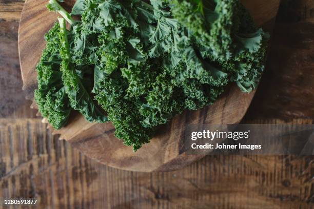 kale leaves on wooden board - grünkohl stock-fotos und bilder