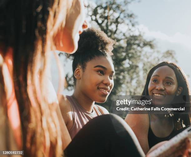 three girls in sportswear relax outside in the sun - mental wellbeing foto e immagini stock