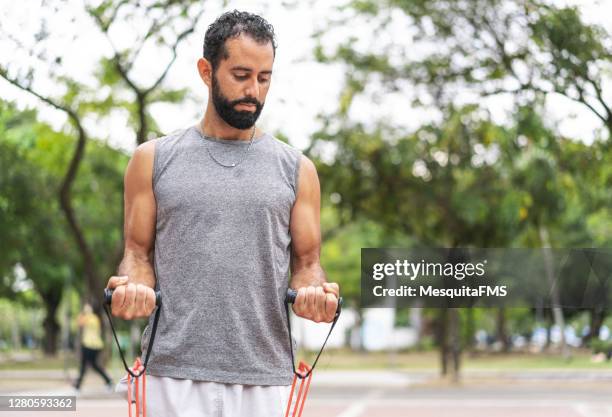 homem treinando bíceps com elástico ao ar livre - bíceps - fotografias e filmes do acervo