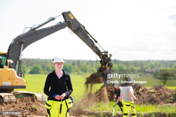 female worker with digger on background - anthropology stock pictures, royalty-free photos & images