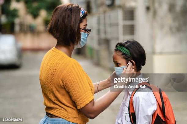 indian mother helping her daughter to put protective face mask for protection from coronavirus - india pollution stock pictures, royalty-free photos & images