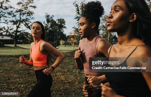 personal trainer motivating jogging clients - grupo de competencia fotografías e imágenes de stock