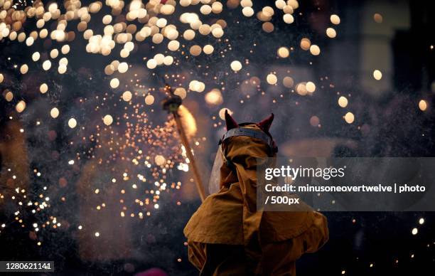 man wearing costume while standing against firework display at night, via laietana, barcelona, spain - correfoc stockfoto's en -beelden