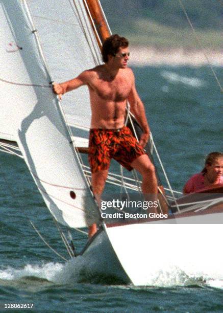 John Kennedy Jr. Stands on the front of a sailboat as he heads out for a sail with relatives.