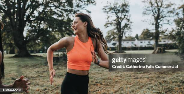 woman jogging in a park - carrera fotografías e imágenes de stock