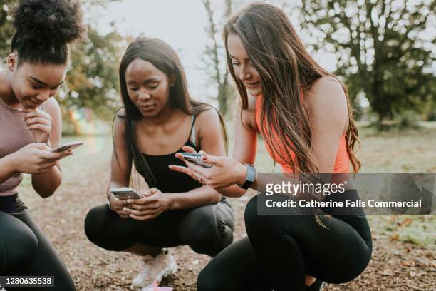 three girls take a rest from exercising to check their phones - pedometer stock pictures, royalty-free photos & images