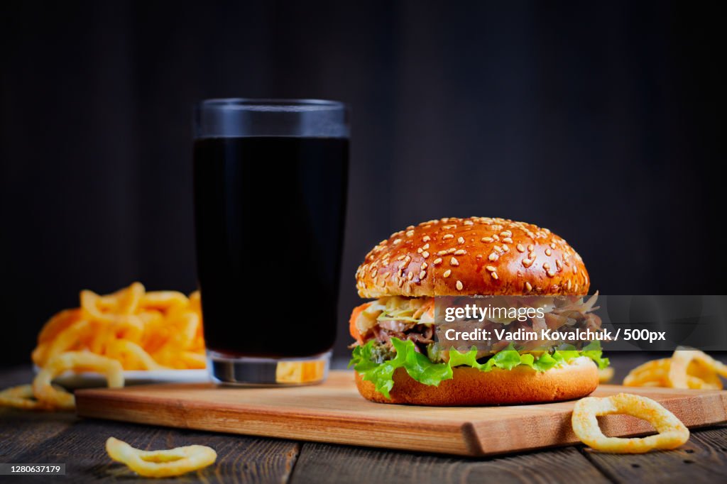 Close-up of burger and french fries on table against black background