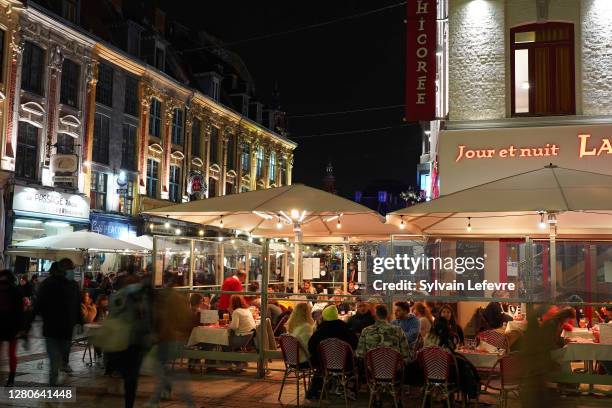 People siting at restaurants terraces and enjoy their plates in downtown of Lille during the last evening before the late-night curfew due to...