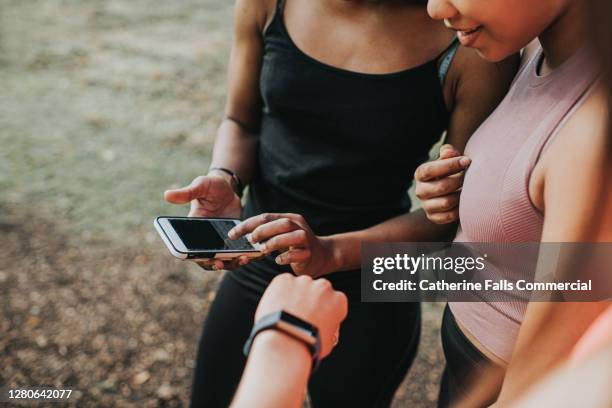 female joggers stop to check their stats on a phone, during exercise - fitness tracker stock pictures, royalty-free photos & images